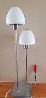 Full view of lamp front showing two shades and chrome base with marker for scale