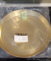 Brass-tone round tray sealed in plastic showing diameter sticker