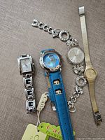 All four wristwatches arranged side by side on fabric surface