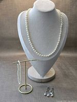 Full lot view: necklace on bust, bracelet on stand, earrings below