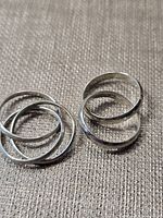 Two sterling silver rings laid flat showing double and triple band structures