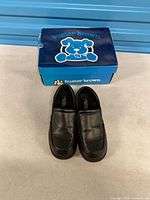 Pair of black Buster Brown Logan shoes with blue box