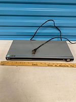 Front and top view of LG LDA-830 player with power cord displayed and ruler for scale