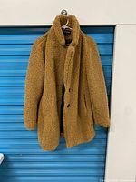 Full view of tan faux shearling coat on hanger