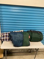 Three sleeping bags on table, rolled