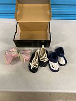 All three pairs of baby shoes and empty Jordan box on table