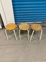 Three wooden-top metal stools side-by-side