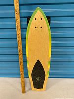 Full top view of skateboard beside yardstick for scale