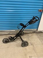Full view of folded TourTrek push cart showing frame and wheels