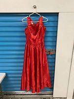 Front view of red satin evening dress on hanger