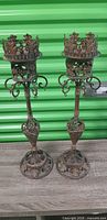 Two ornate wrought iron candle holders full view