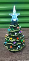 Front view of lit ceramic Christmas tree with star topper and multicolor bulbs