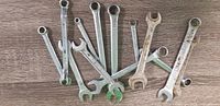 All wrenches spread out showing variety of sizes and both open and ring ends with wear