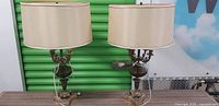 Frontal view of the pair of brass and green glass candelabra lamps with shades