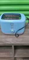Front view of baby blue Dash Rise toaster showing controls and power cord