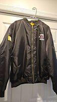 Full front view of black Chicago Cubs 2016 World Series Champions bomber jacket on hanger