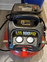 Full view of air compressor showing tank, handle, gauges, fittings