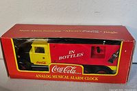 Front of boxed Coca-Cola alarm clock showing truck design and product text