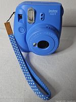 Front view of blue Instax Mini 9 with wrist strap attached