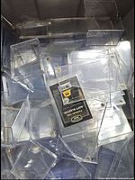 Bin of mixed clear plastic card storage items with BCW soft sleeves pack visible