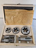 Open wooden case showing three dies and three taps in place