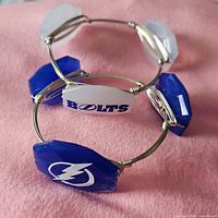 Both bracelets showing alternating blue and white logo stones