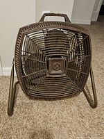 Front view showing square brown grille, fan blades, and metal tilt stand