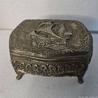 Closed box front angle showing sailing ship relief and ornate border
