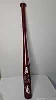 Full view of maroon wooden baseball bat upright