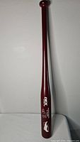 Full view of maroon wooden bat upright