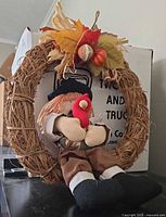 Front view of grapevine wreath showing scarecrow, leaves, pumpkins and raffia bow