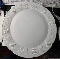 Front view of milk glass torte plate showing Harvest grapevine relief