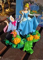 Front view of resin stocking hanger showing Cinderella, Fairy Godmother, pumpkins and base