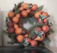 Front view showing dried gourds, faux pine, pine cones, holly leaves and berries