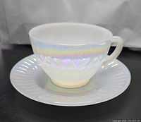 Angled view of cup on saucer showing iridescent finish and diamond pattern