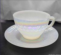 Iridescent milk glass teacup on saucer showing diamond and fluted patterns