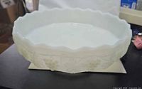 Side view showing scalloped rim and embossed grapevine pattern on white milk glass bowl