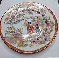 Front of porcelain plate showing multicolor figural and floral decoration with red-orange gilt rim