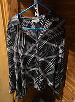 Front view of black and white abstract blouse on hanger