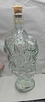 Full view of light green glass decanter showing grape motif and stopper