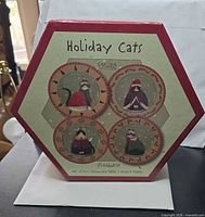 Front of original hexagonal box showing four Holiday Cats plate designs and branding