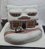 Front view showing sign, figures, lights, snowy roof