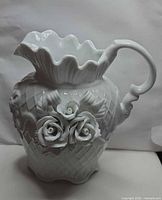 Front view showing basket weave body, three bisque roses, ruffled rim, scroll handle