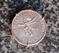 Obverse of coin in bezel showing Aztec figure, Olympic rings, legend