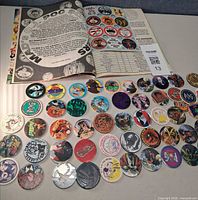 array of pogs laid out with open POG magazine showing additional designs