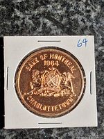 Obverse of 1964 Bank of Montreal centennial token in holder showing legends and coat of arms