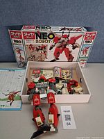 Box lid with NEO ROBOT-1 artwork, open tray showing parts, instruction sheet and partially built limb