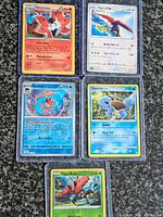 All five Pokémon cards in sleeves displayed on surface