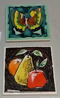 Both ceramic tiles front view, fruit and butterfly designs
