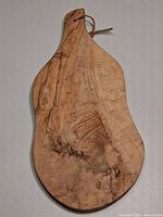 Front view of olive wood board showing grain, handle, leather loop